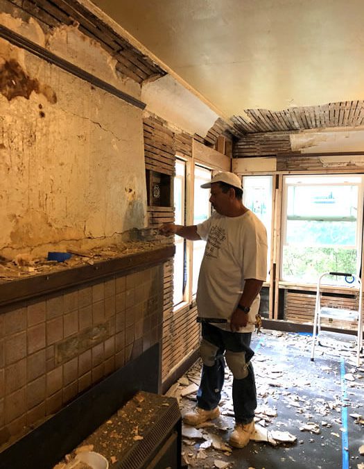 Removing damaged plaster from lath and plaster walls and fireplace chimney.